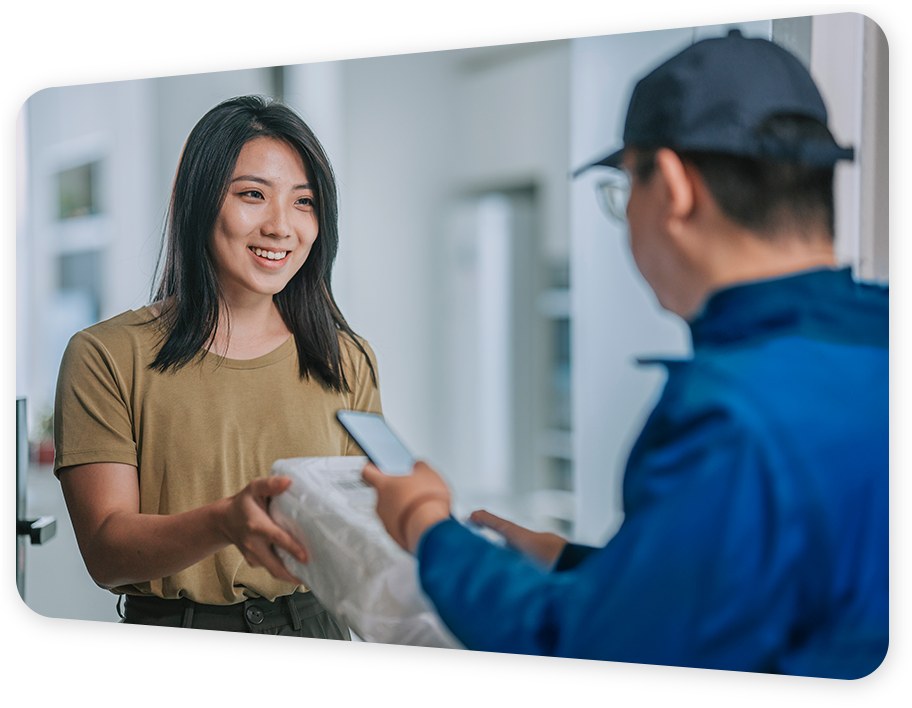 A smiling lady receiving a parcel from a delivery man
